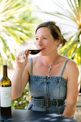 Woman sipping red wine outdoors.
