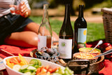 The Napa Table Trio surrounded by vegetable and cheese trays on a red picnic blanket