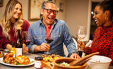 ||||A smiling girl with long blonde hair stretches her arm across a table while holding a wine glass on the Clif Family patio while others join their glasses with hers for a cheers.||||Clif Family Farm|