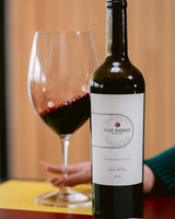 Bottle of Clif Family Winery Cabernet Franc with a glass of red wine on a wooden table.