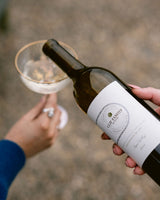 Person pouring a bottle of Clif Family Napa Valley Sauvignon Blanc into a glass outdoors.