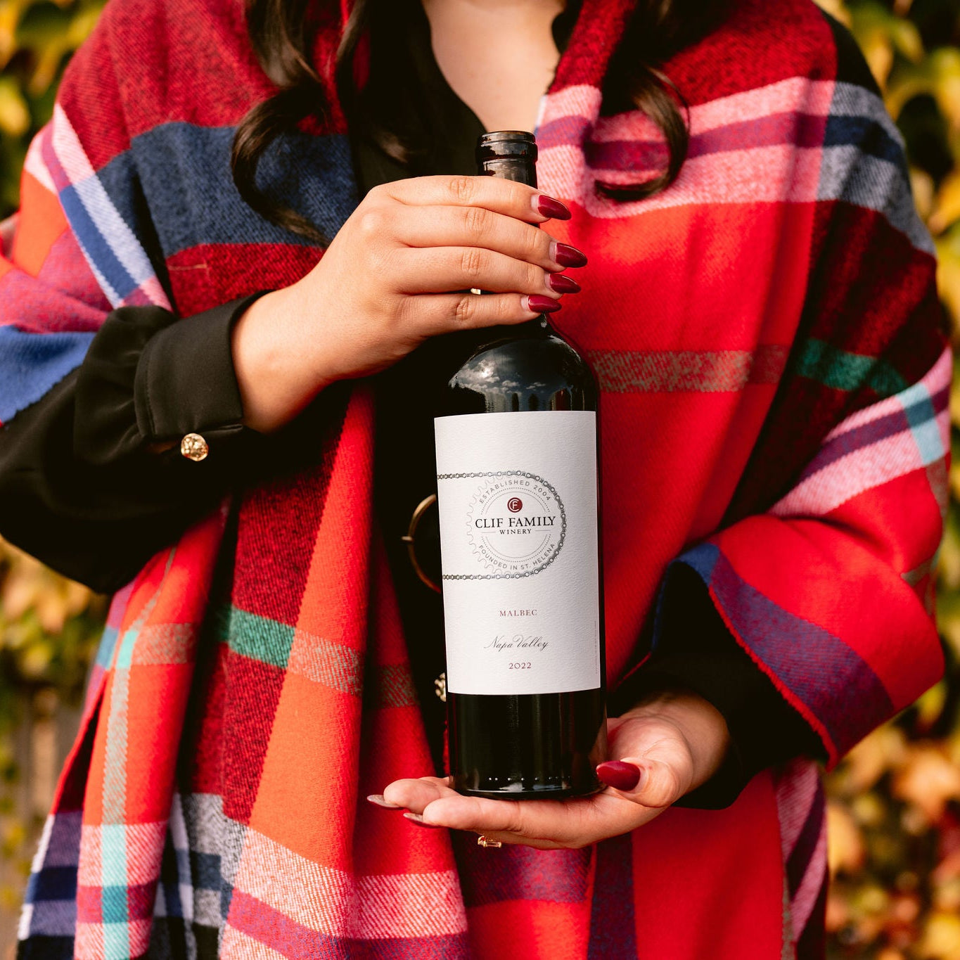 Woman in a plaid sweater holding a bottle of red wine