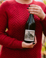 Person wearing a red sweater holding a bottle of Clif Family Bici, Red Rhone Style Blend.