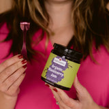 Woman smiling and holding Clif Family Organic Blackberry Jam