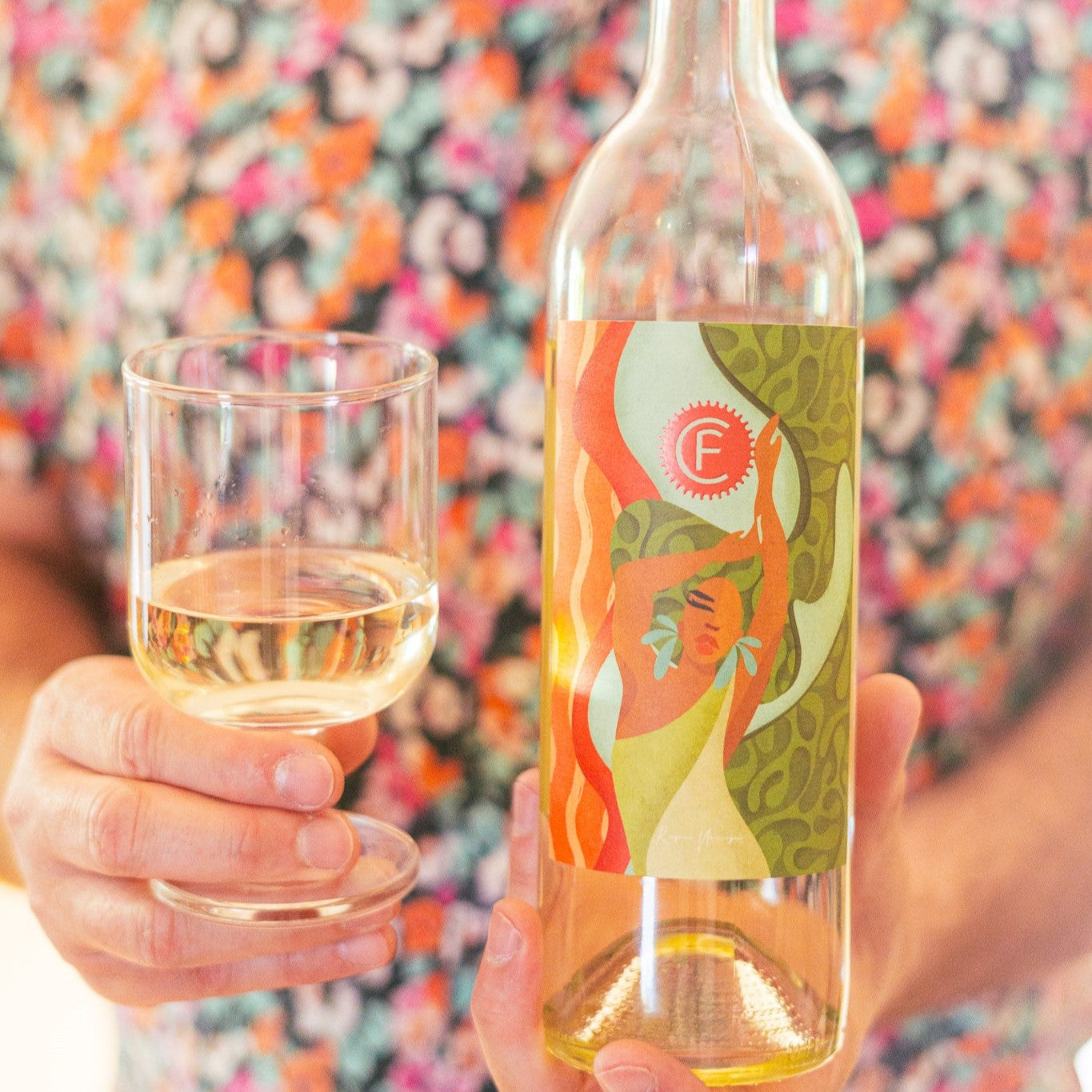Man in a flowered shirt holding a bottle of white wine