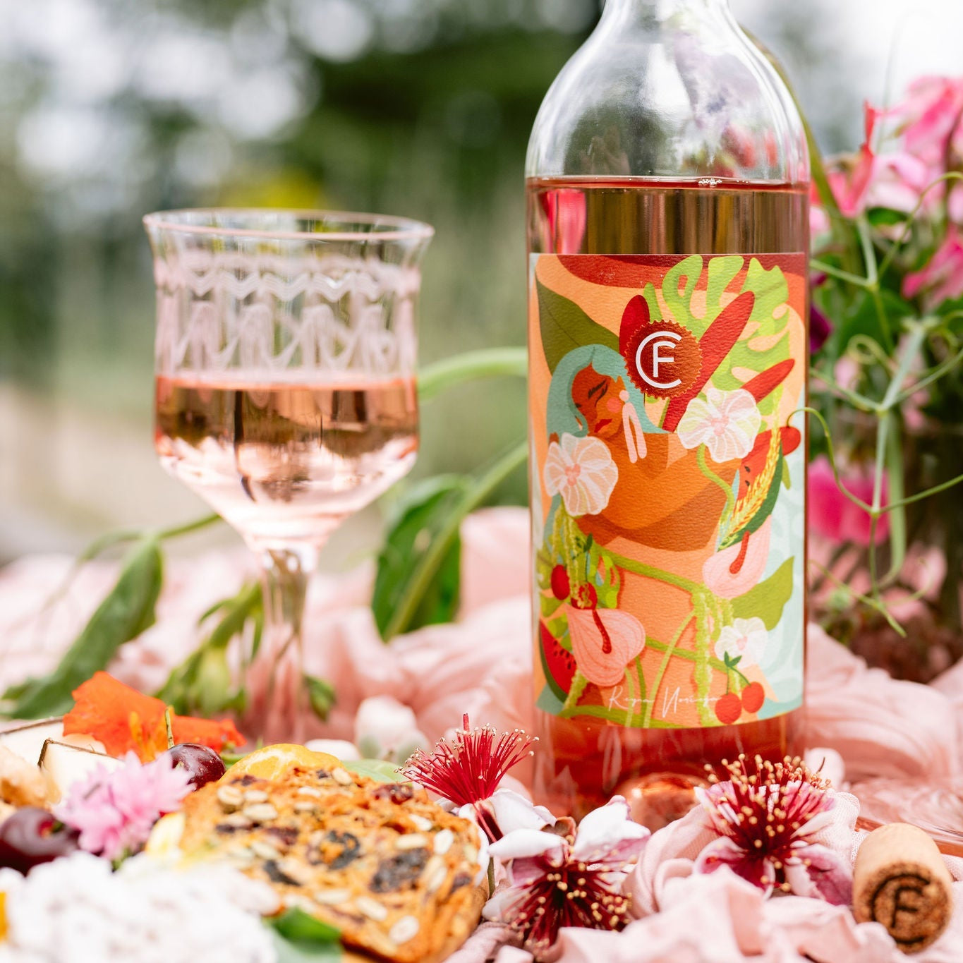 Bottle and glass of 2025 Clif Family x Reyna Noriega Rosé of Cabernet Franc surrounded by flowers