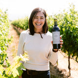 Woman in vineyard holding a bottle of red wine