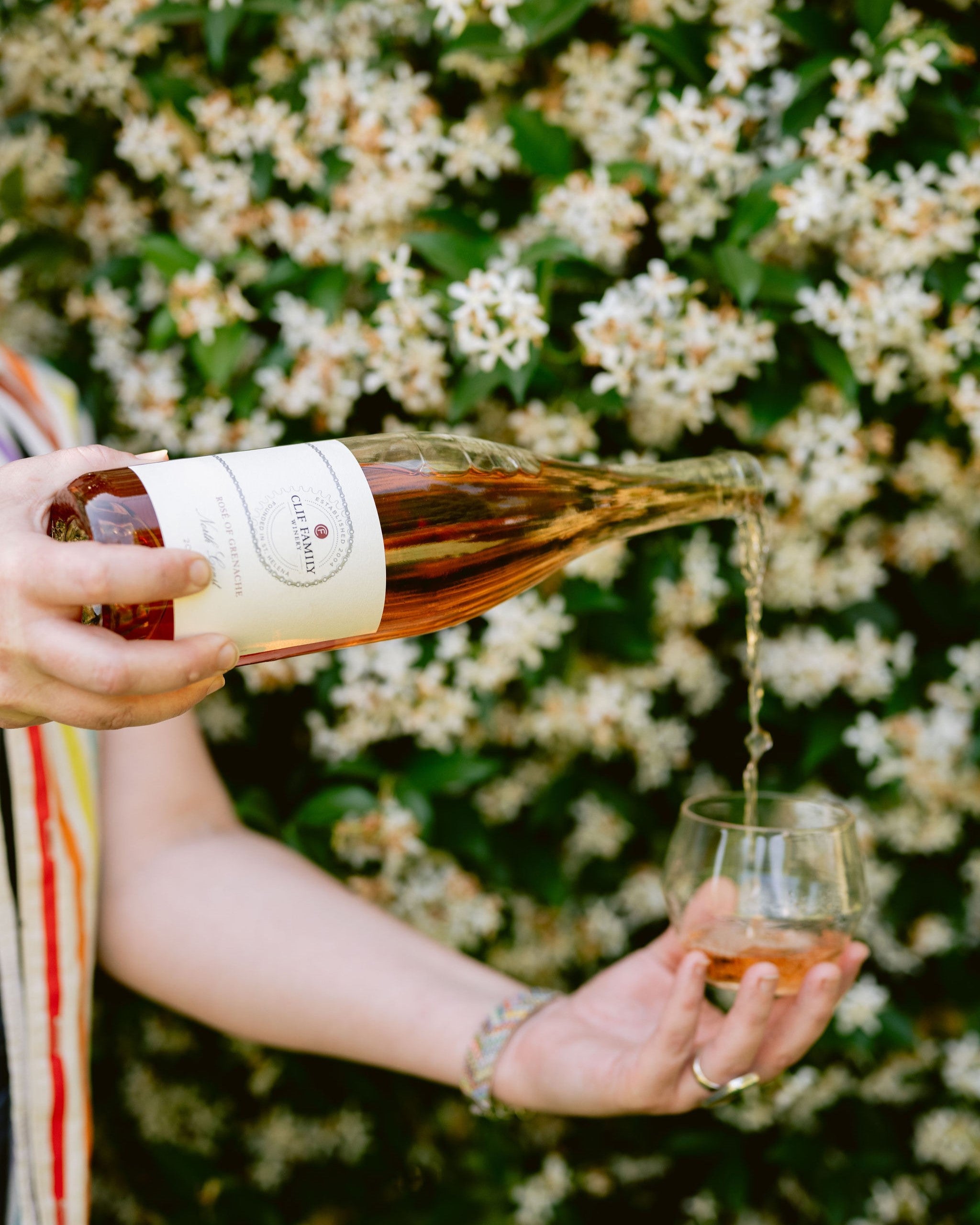 Person pouring rosé wine into a glass with a floral background
