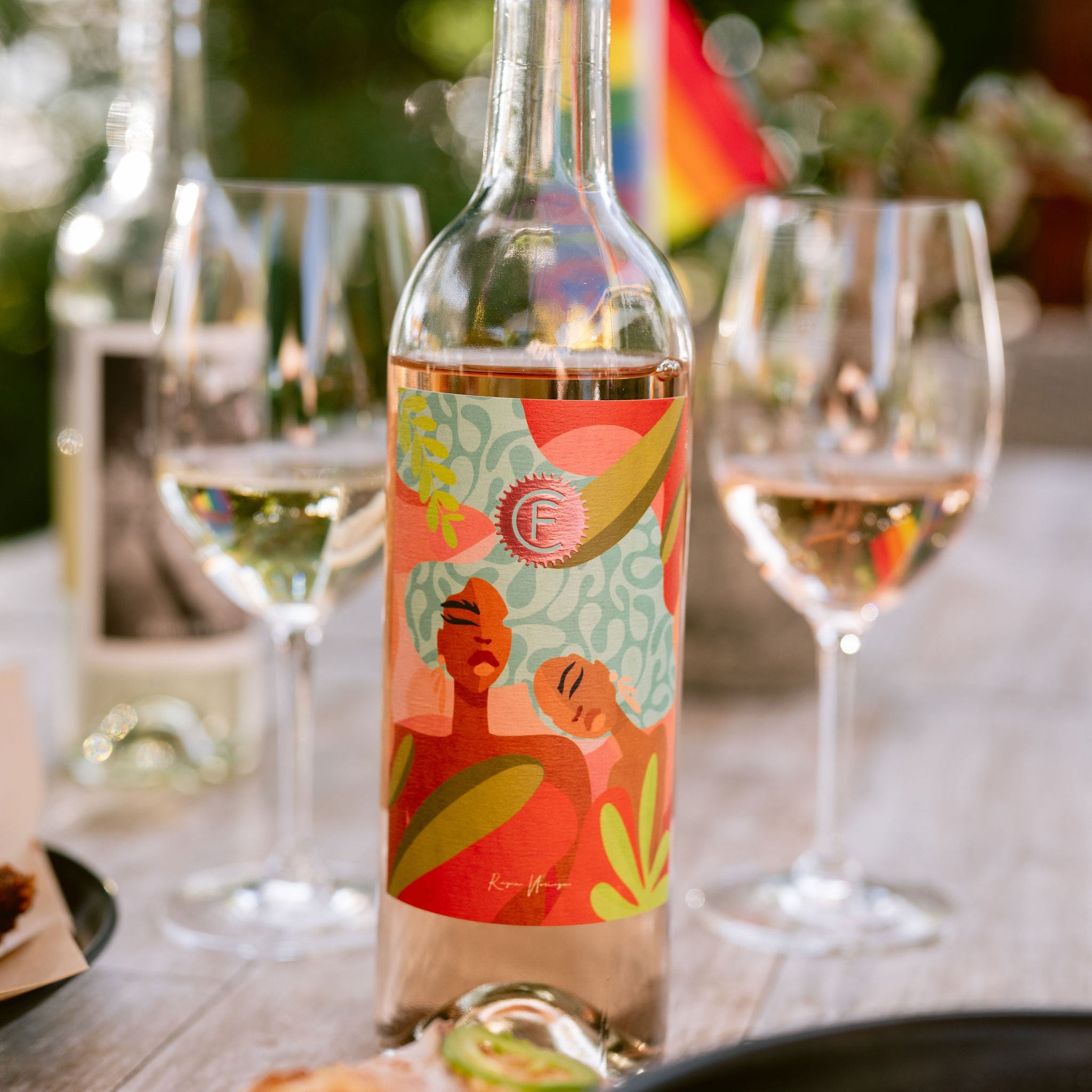 Bottle of wine with a colorful label on a table with glasses and food