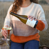 Woman sitting in field pouring a glass of white wine