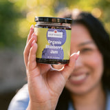 Woman smiling and holding Clif Family Organic Blueberry Jam