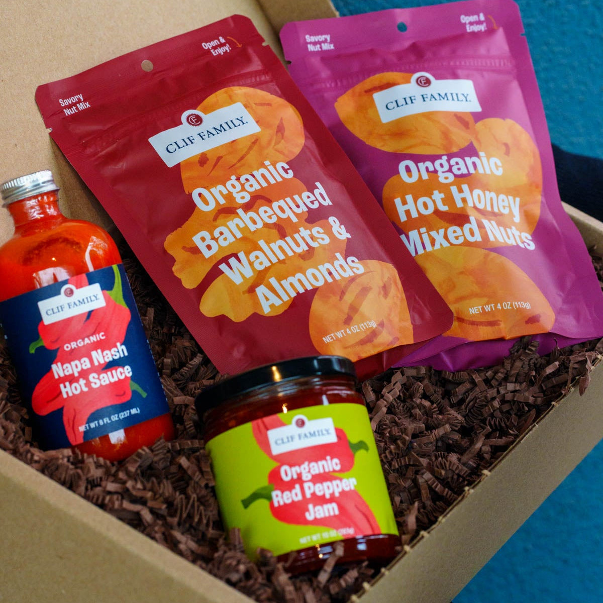 Assorted organic snacks including nuts, hot sauce, and jam in a box.